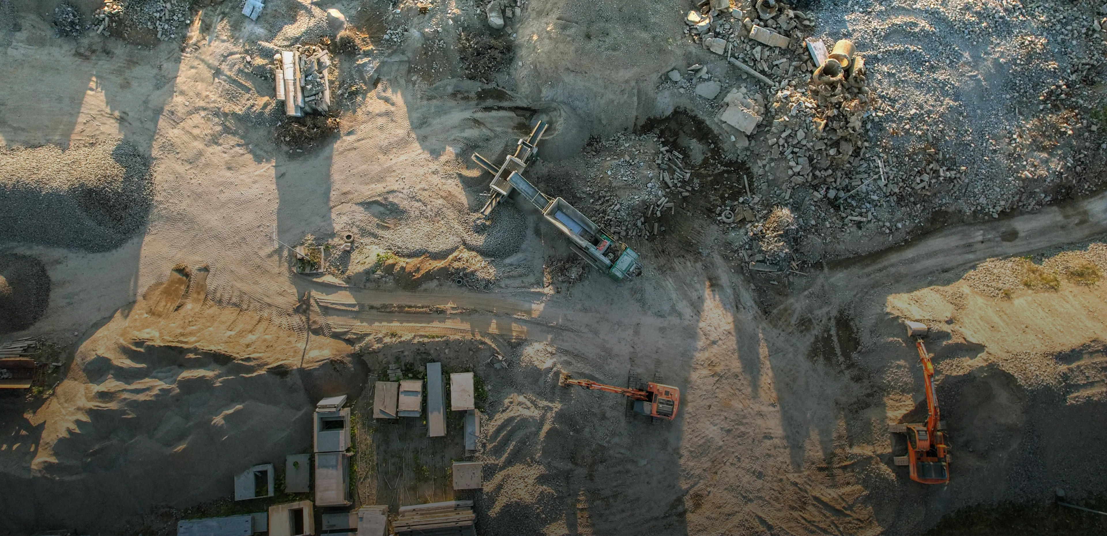 Große Baustelle mit Sandboden und mehrern Baggern von oben fotografiert